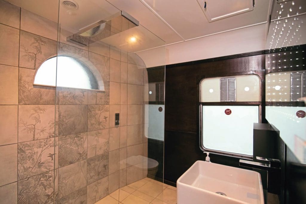 The bathroom, with toilet, sink, infinity mirror and tiled wet room.